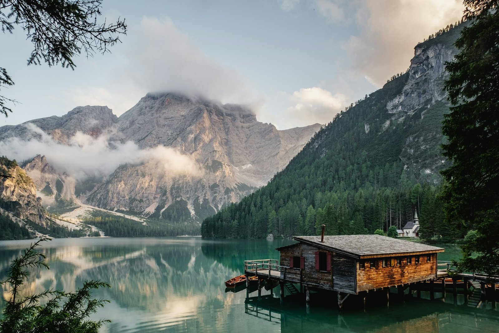 A cabin by a still lake beneath mountains
